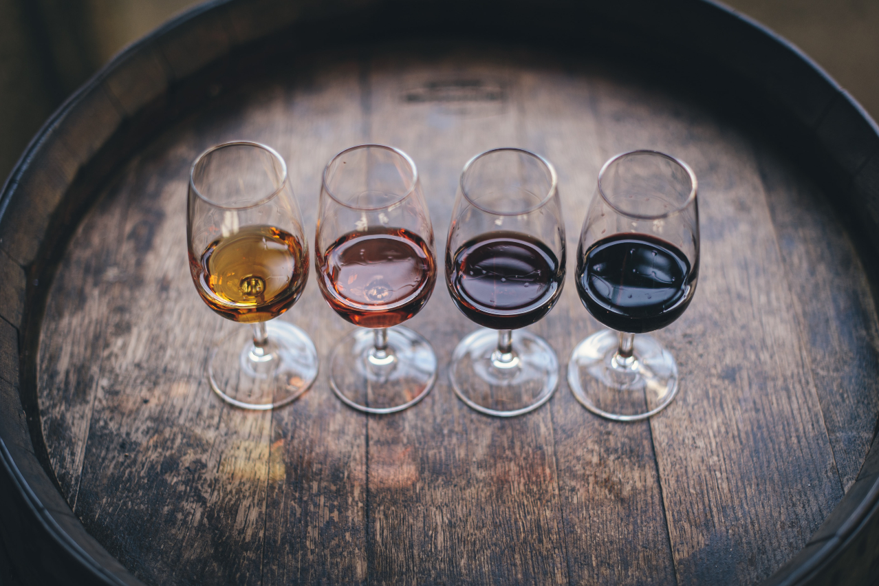 Four wine glasses on top of an oak barrel