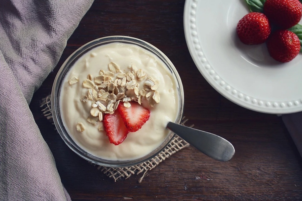 Bowl of yogurt with oats and sliced strawberries.