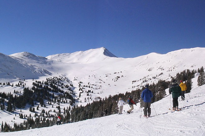 Five skiers at the top of a slope