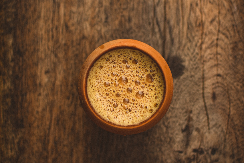 Small clay cup of Indian chai on a wooden table.