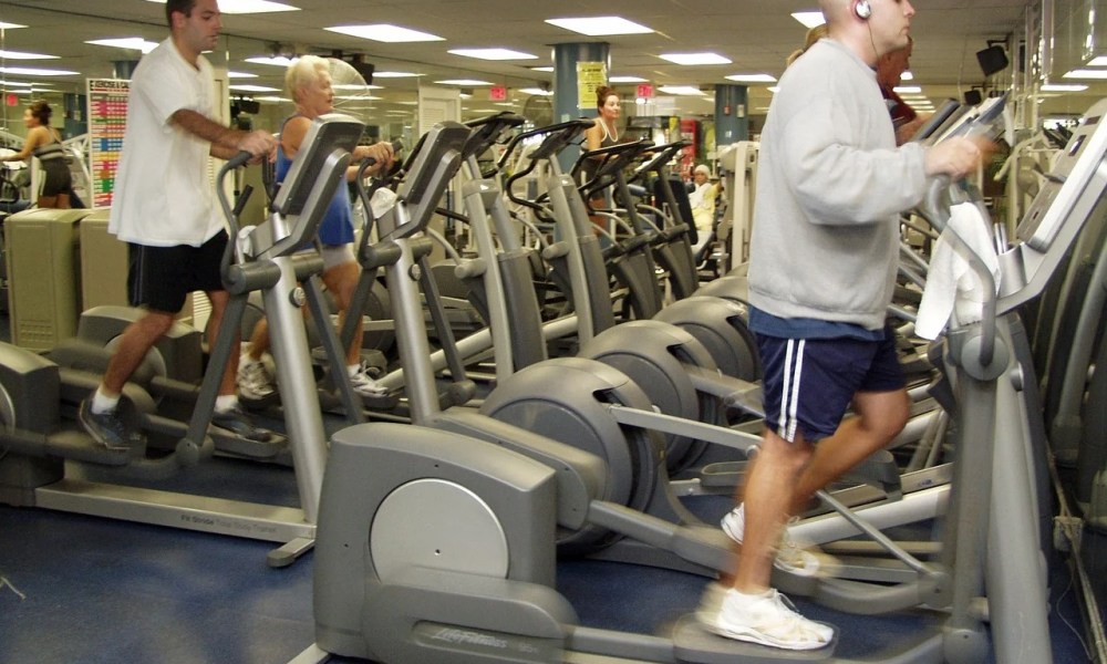 Men using elliptical trainers at a gym