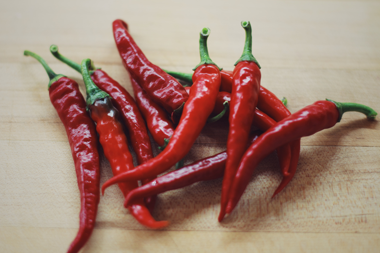 Handful of fresh red chili peppers on a wooden table.