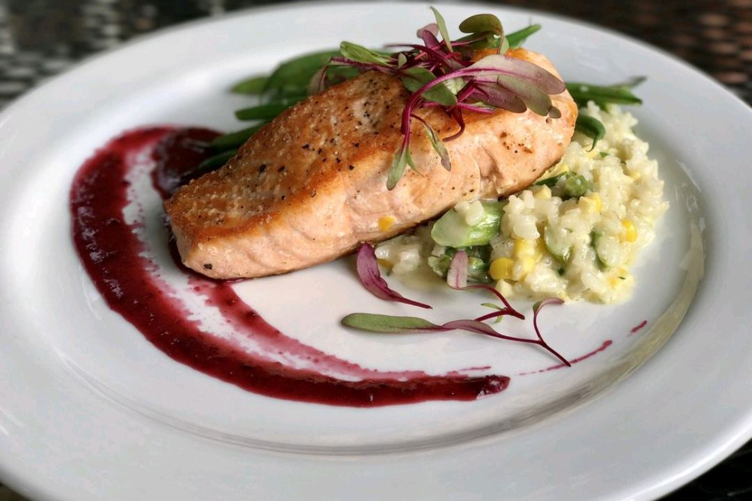 pan fried salmon filet on a plate with side dish and garnish.