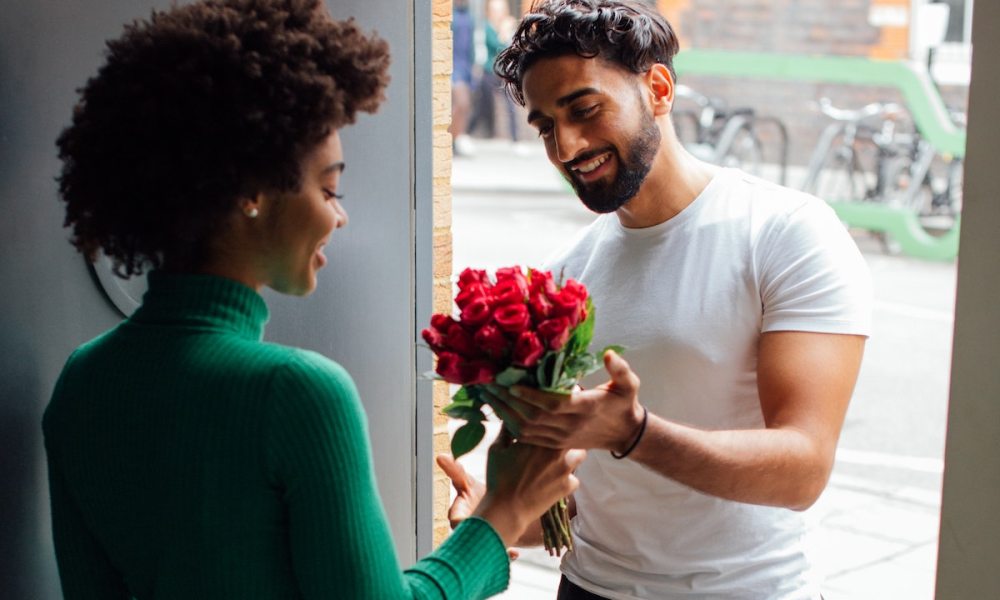 Man giving woman a bouquet or red roses.