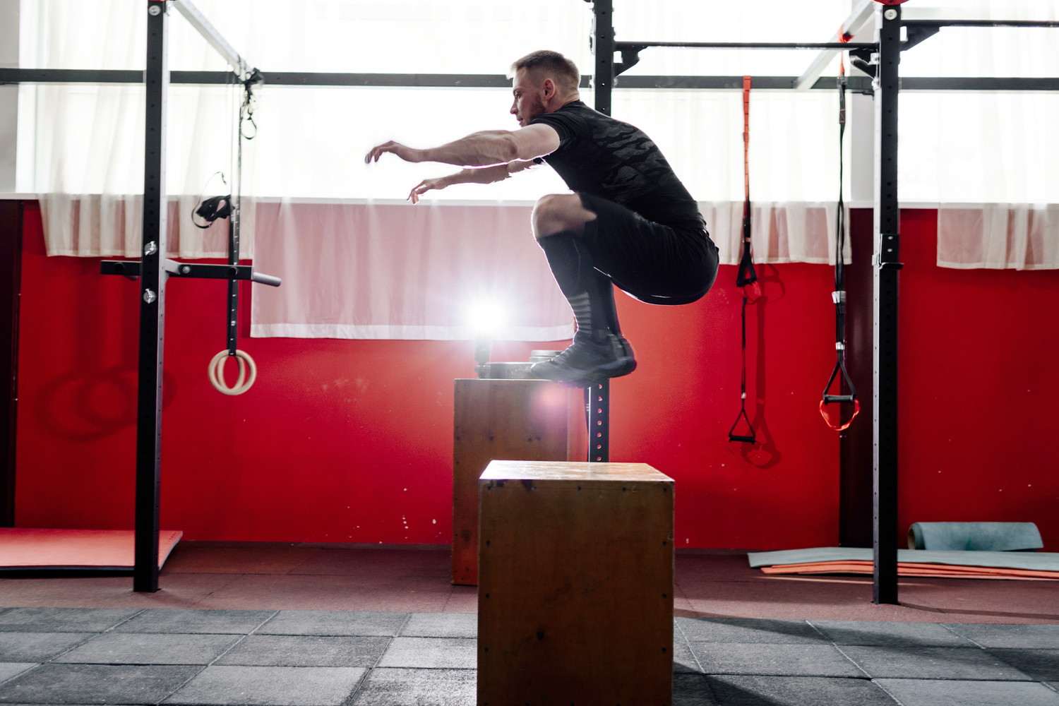 A man doing a box jump in a gym.