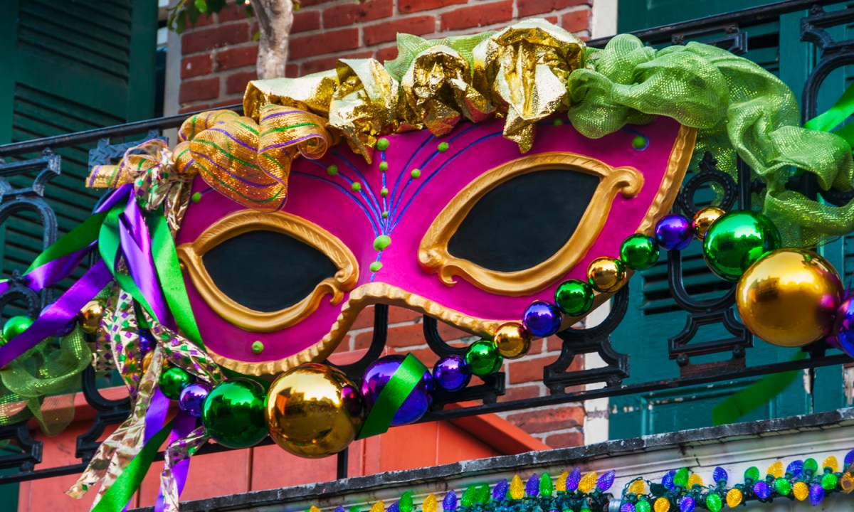 A large Mardi Gras mask on a balcony railing.