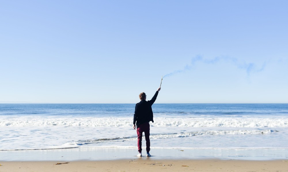 A man on a beach using a smoke signal.