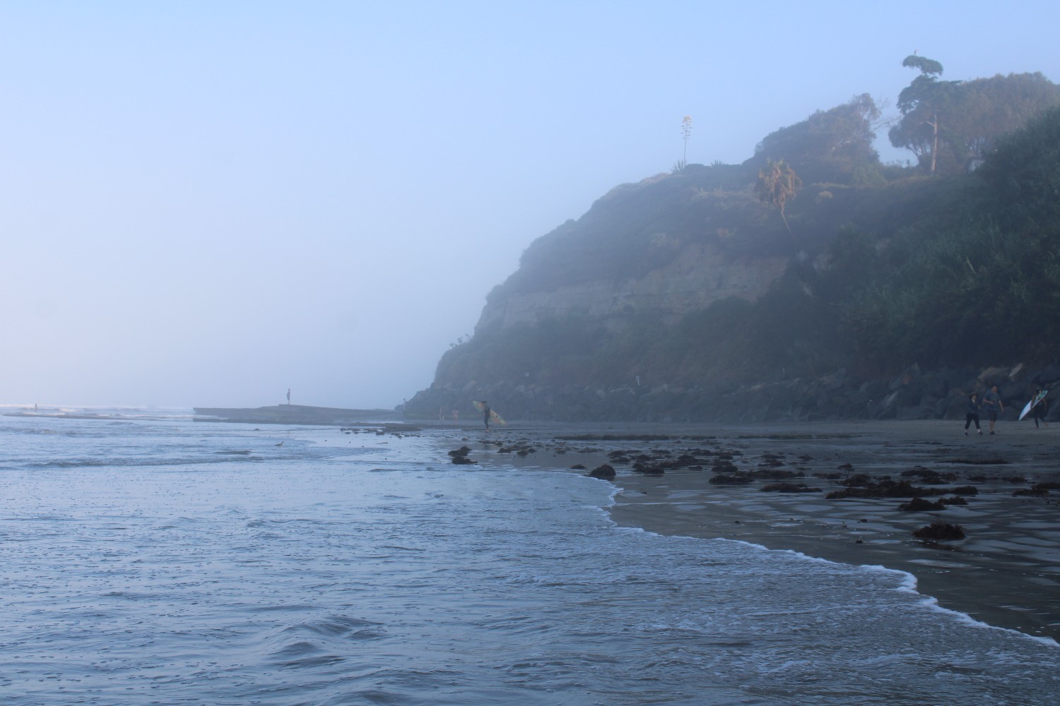 Surfers walk the beach at Swami's Beach in Encinitas, California.