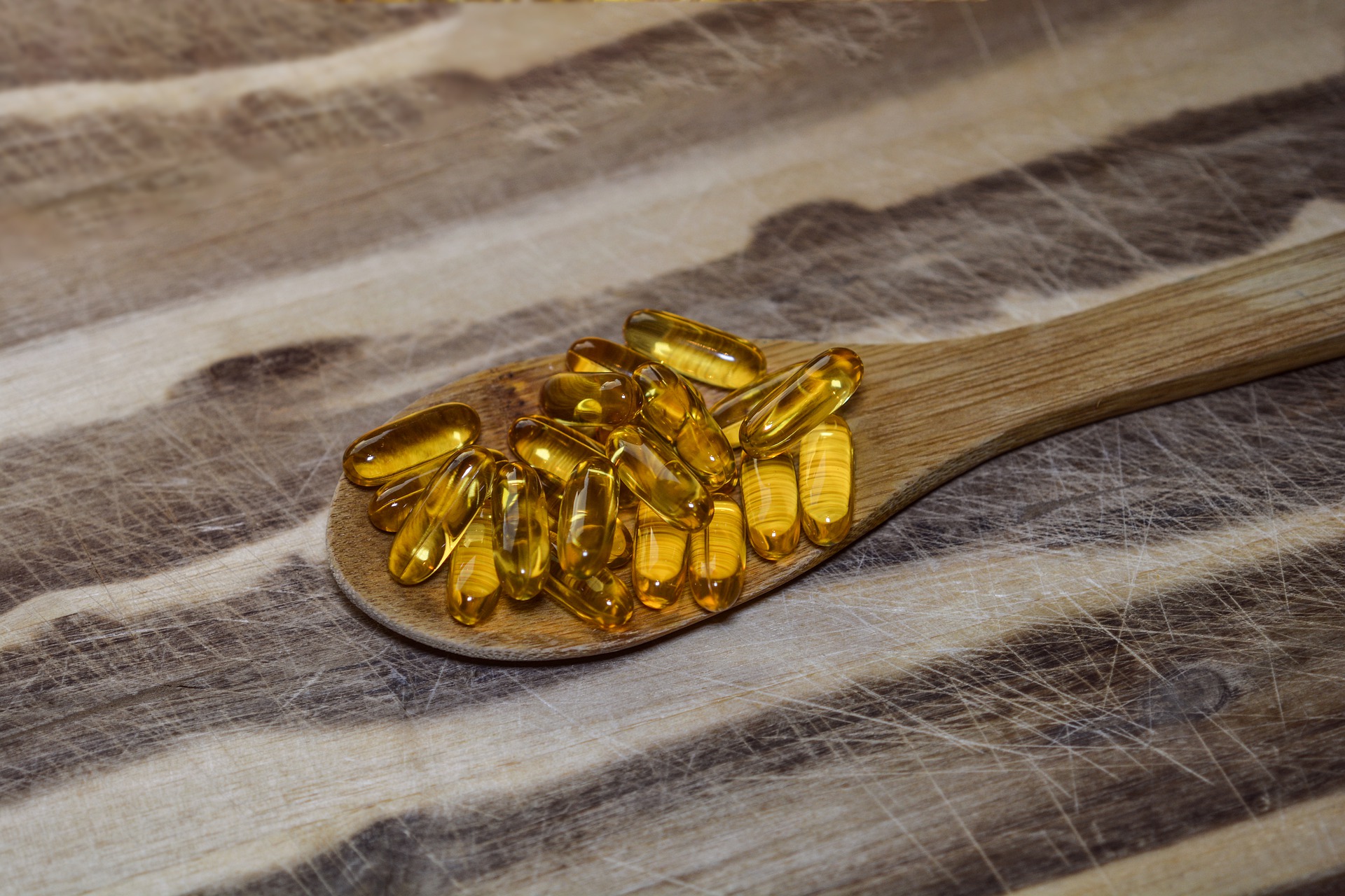 A spoonful of cod liver oil supplements on wooden background.