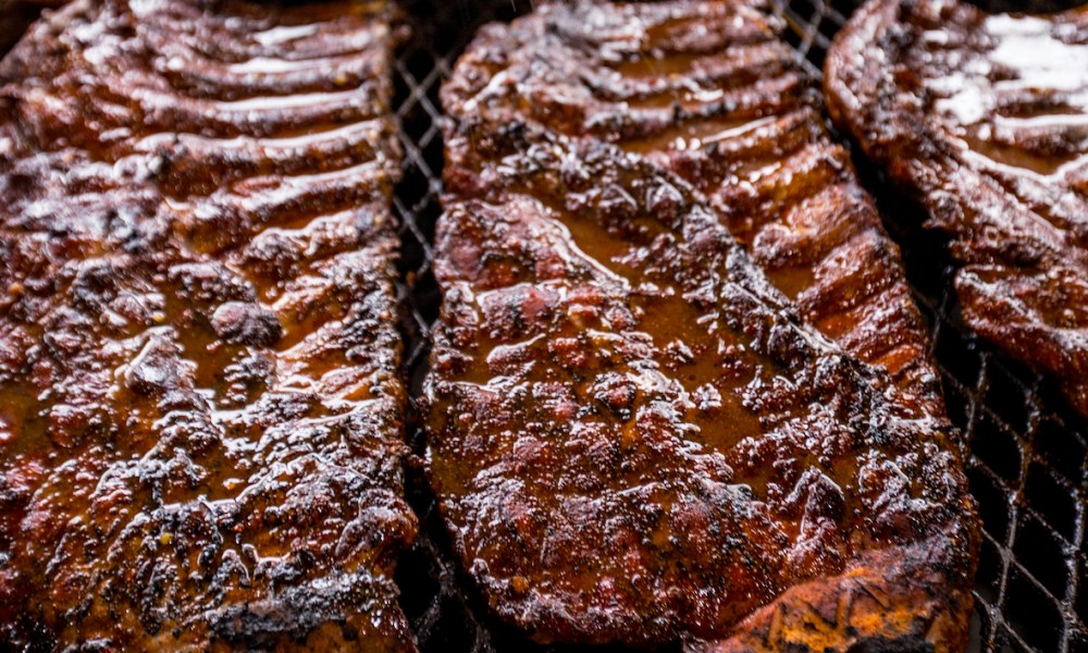 Several racks of Rodney Scott ribs in a smoker.