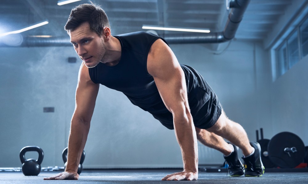 A man doing pushups in a gym.