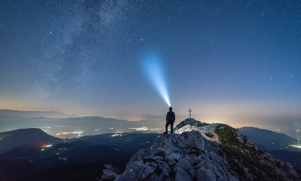 Man on a mountain with the best headlamp of 2022.