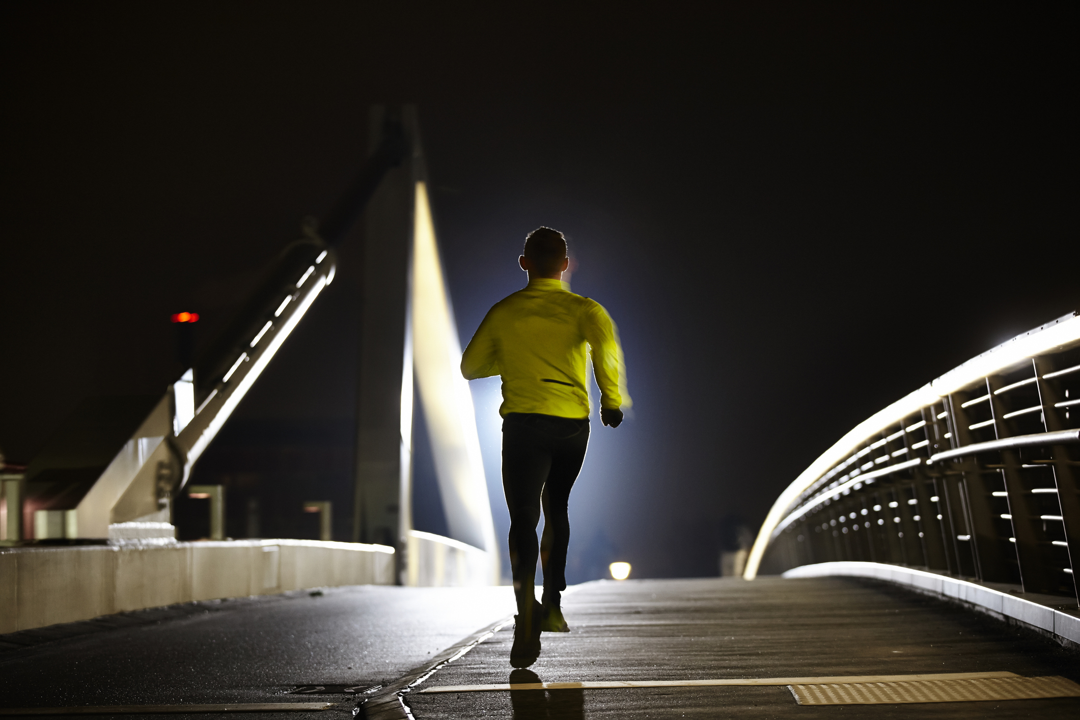 Man running along at night on a bridge