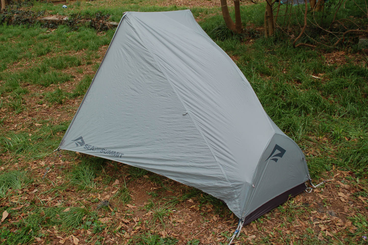 A one-person backpacking tent with the rainfly staked out.