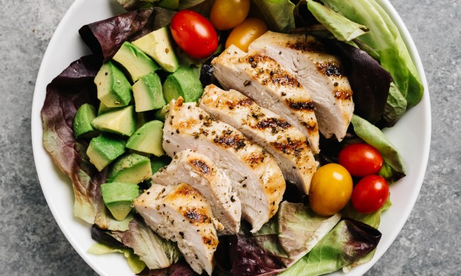 An overhead shot of a bowl of grilled chicken salad on a table.