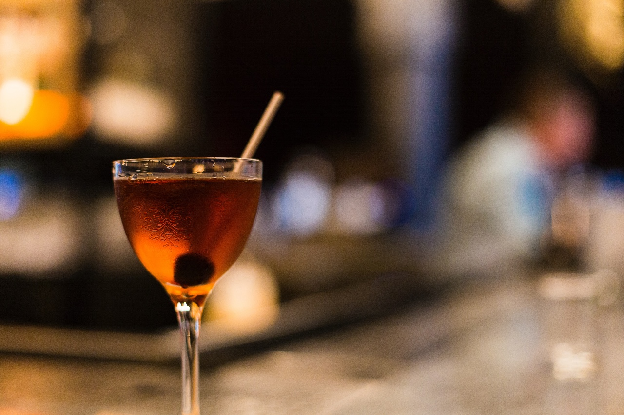 A Manhattan cocktail in a stemmed glass sits on a bar.