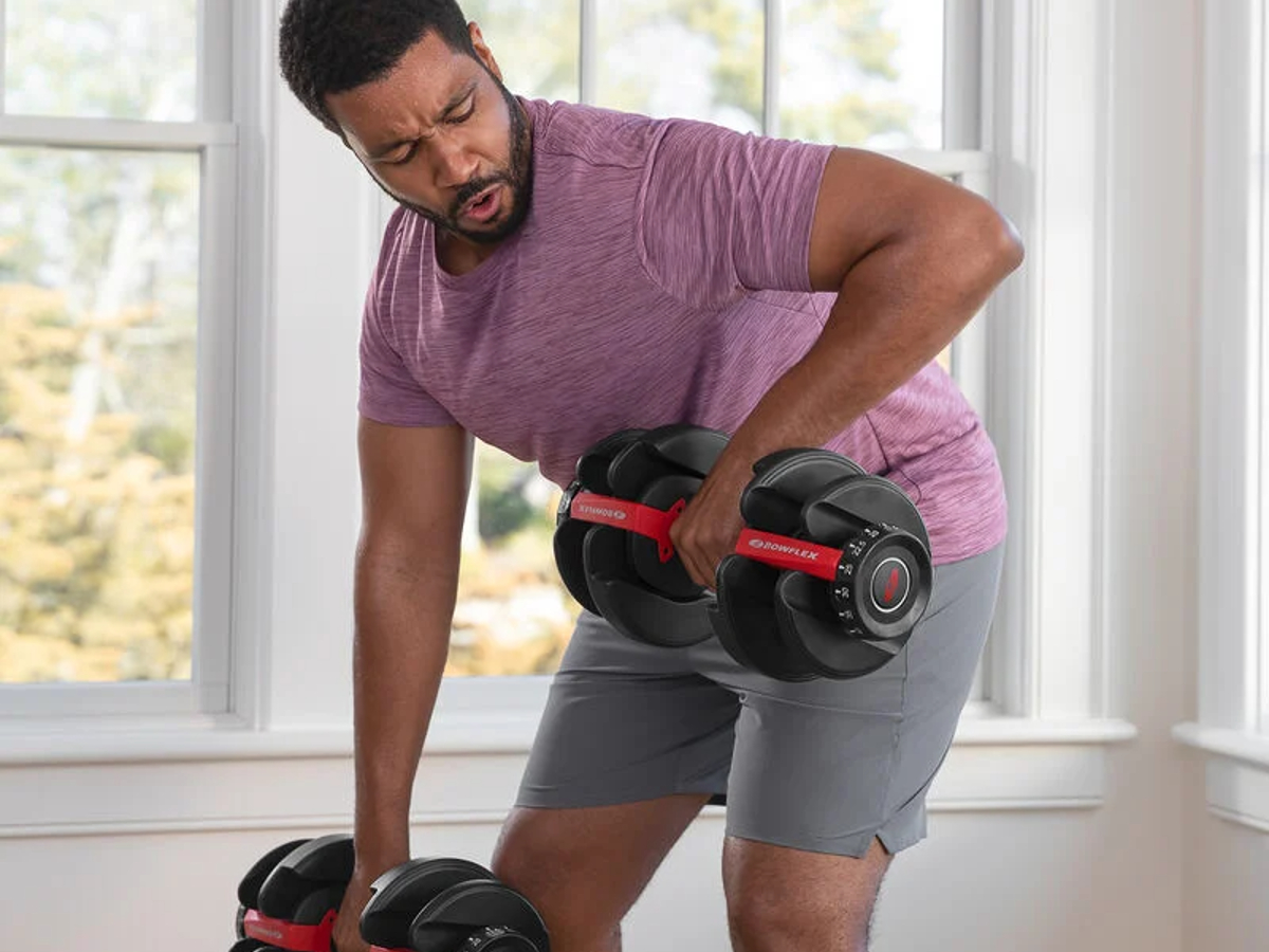 A man lifting with Bowflex adjustable dumbbells in his home.