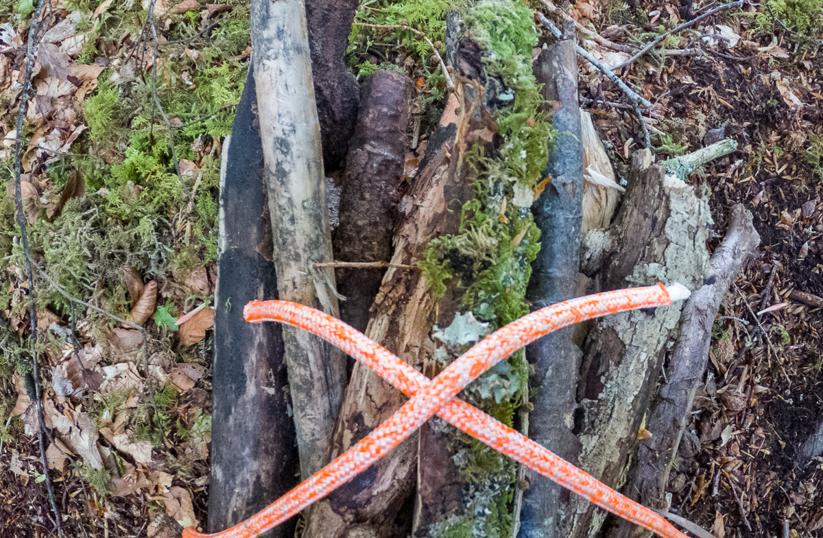 Step 1 of tying a square knot around a bundle of wood