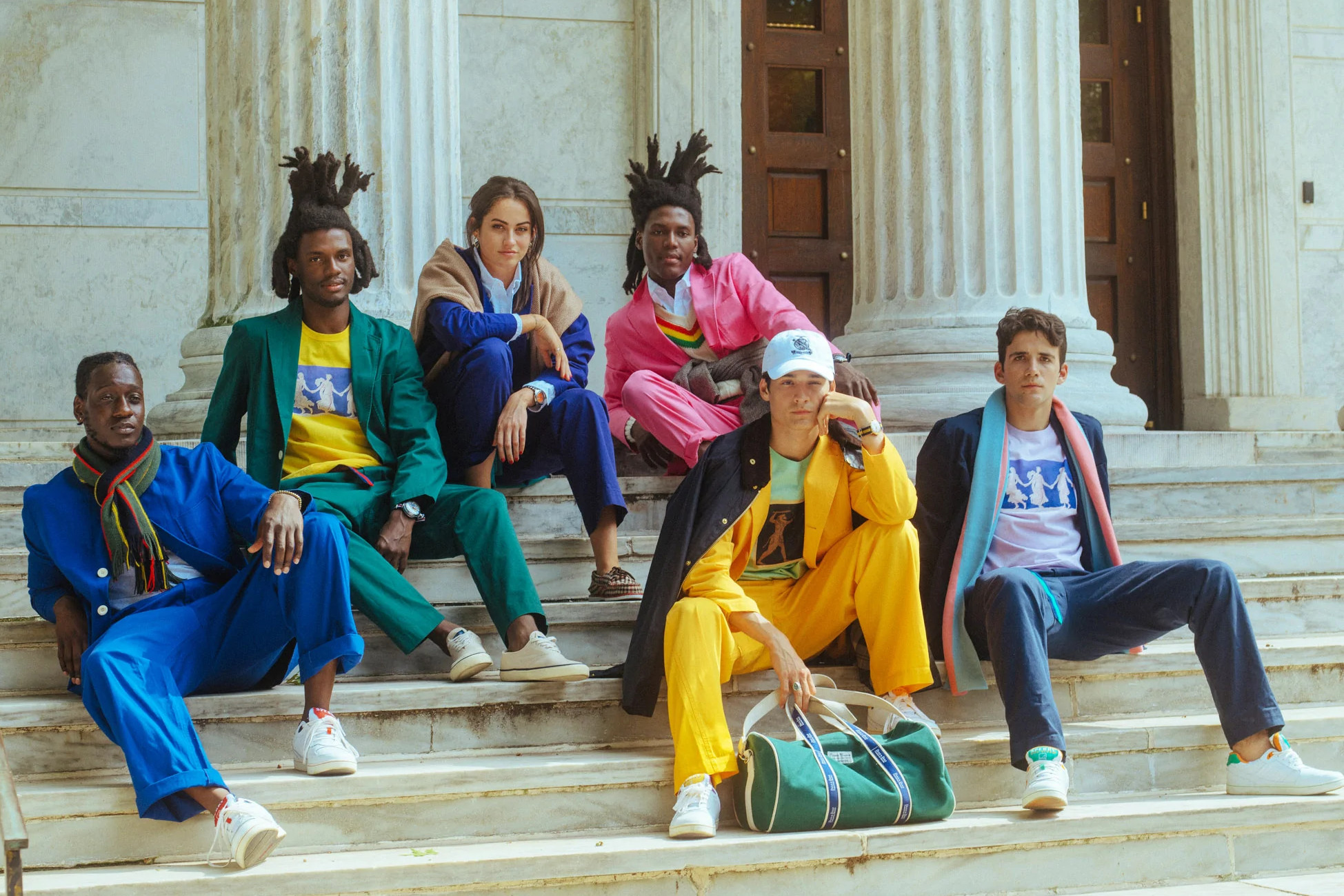 A group of people in colorful suits sitting on the steps of a library.