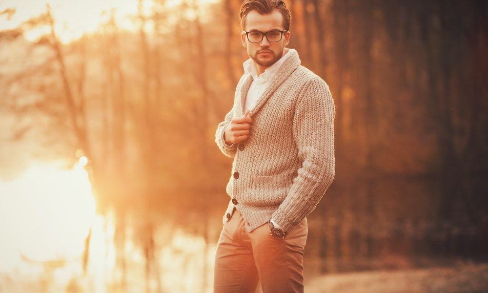 Trendy handsome man posing in autumn park alone