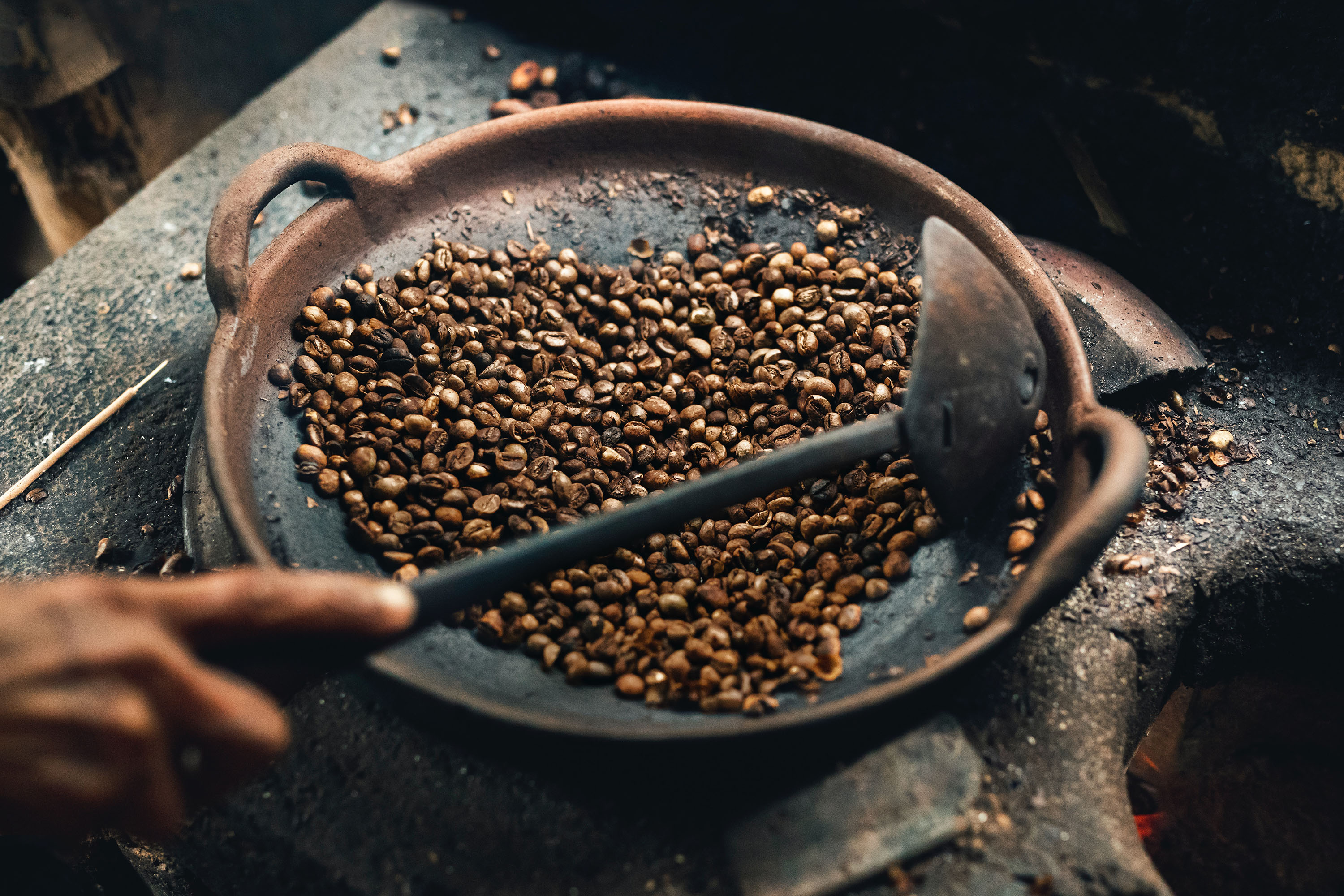 Person roasting coffee beans in a wok