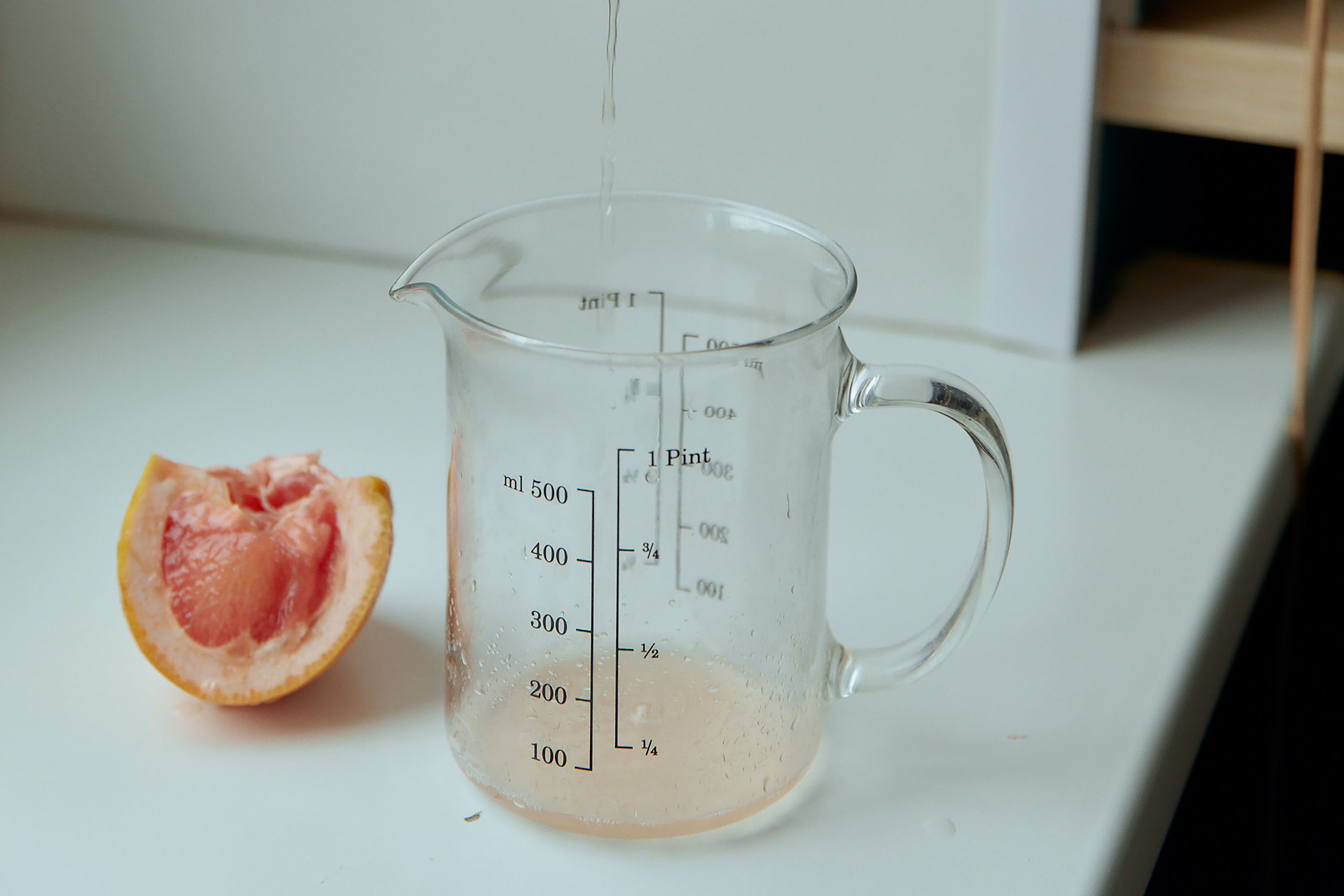 Person squeezing grapefruit into a mL container