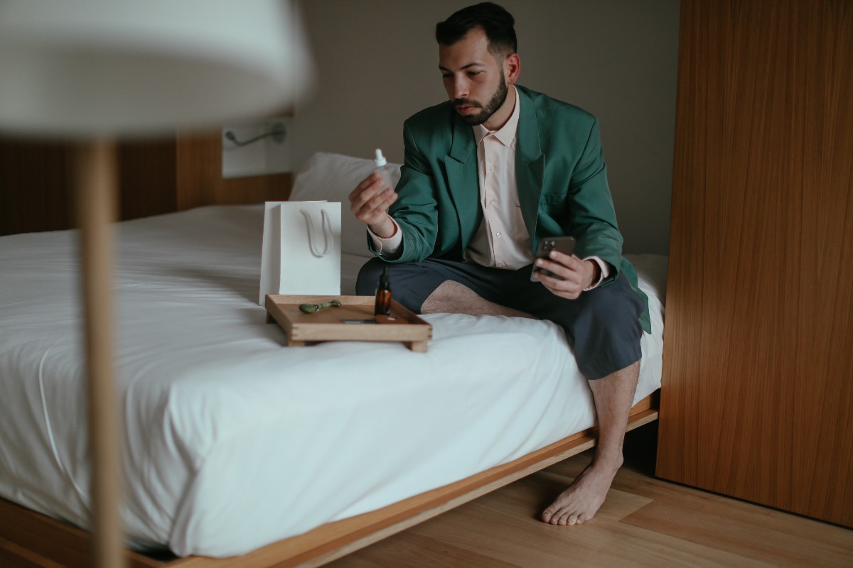 Man looking at skincare products in bed