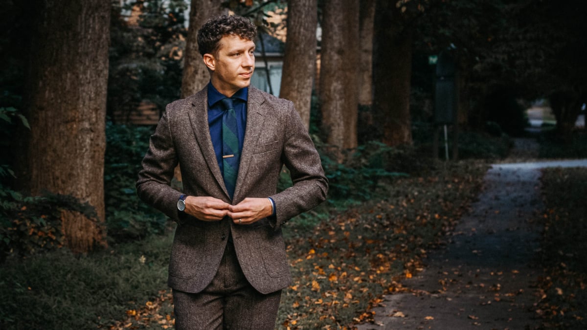 Man buttoning up a tweed suit jacket