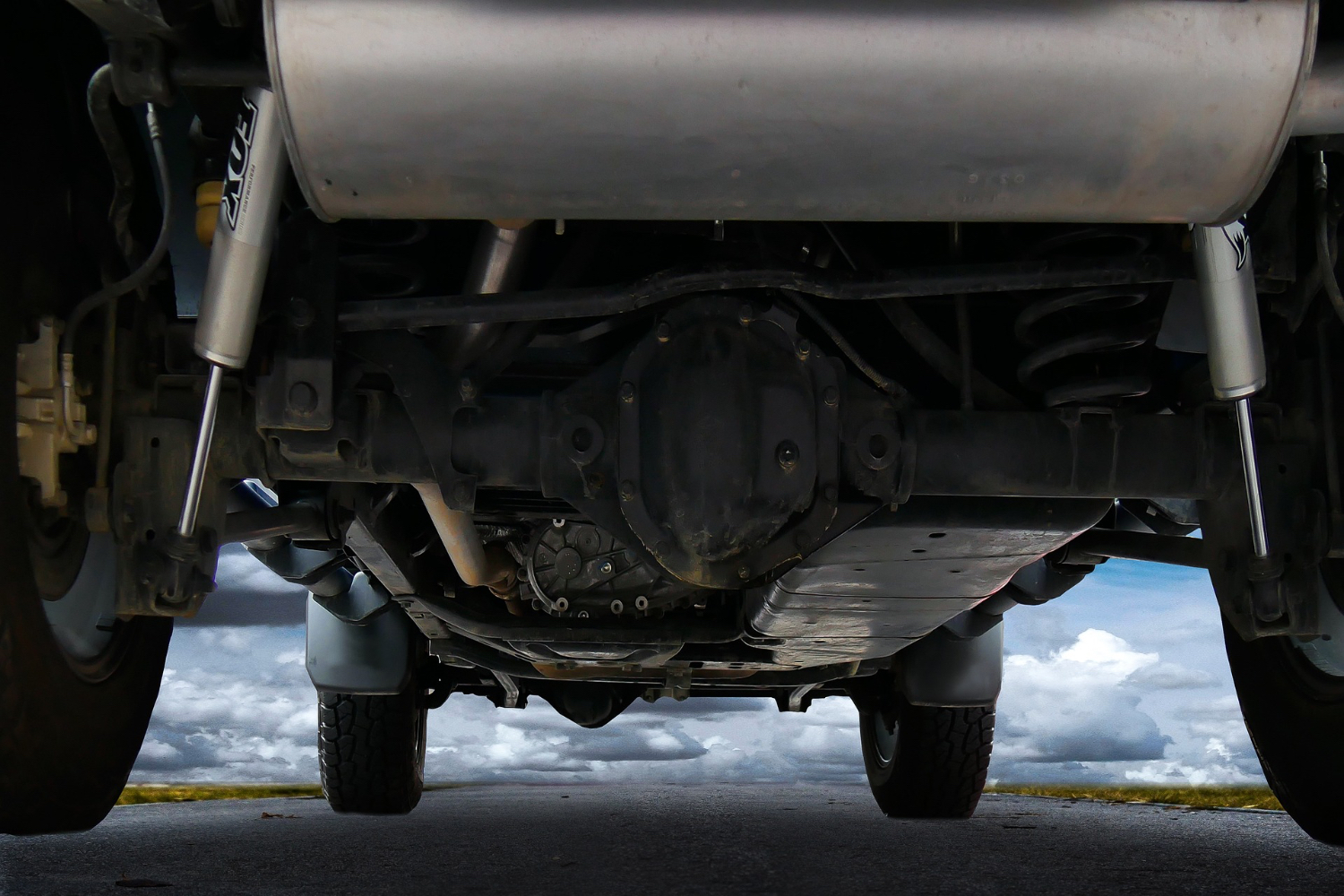 Close up of underneath a lifted car sitting on the side of the road with a look at the differential.