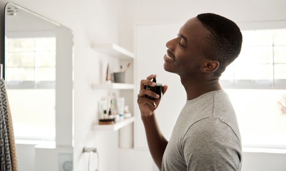 Person spraying cologne on their neck