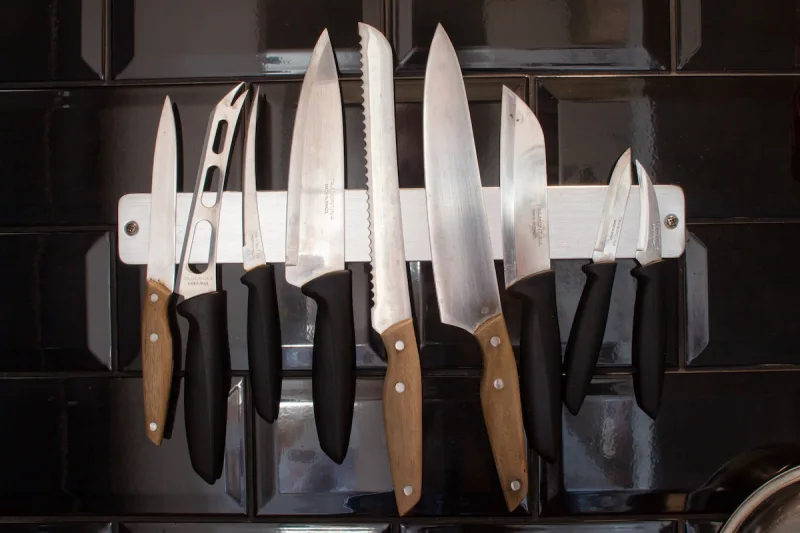 An array of knives stuck to a magnet in the kitchen