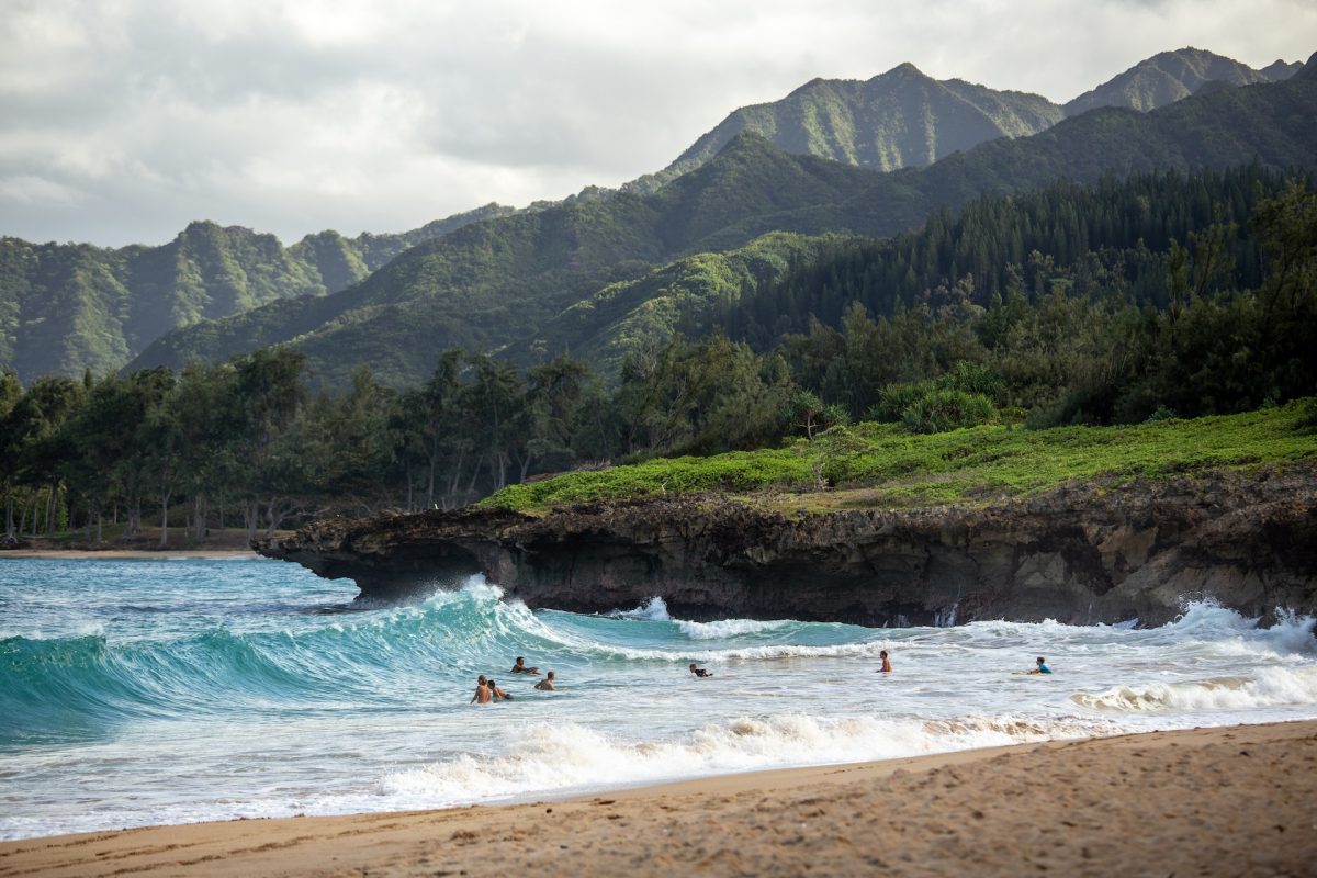 A shot of a beach in Hawaii with people in the water.