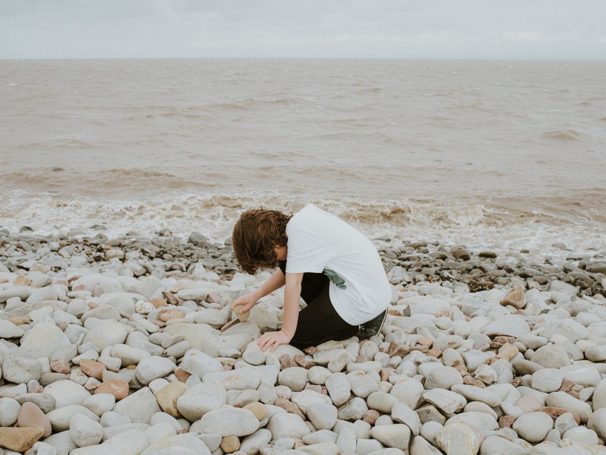 A person digging in the rocks on the beach