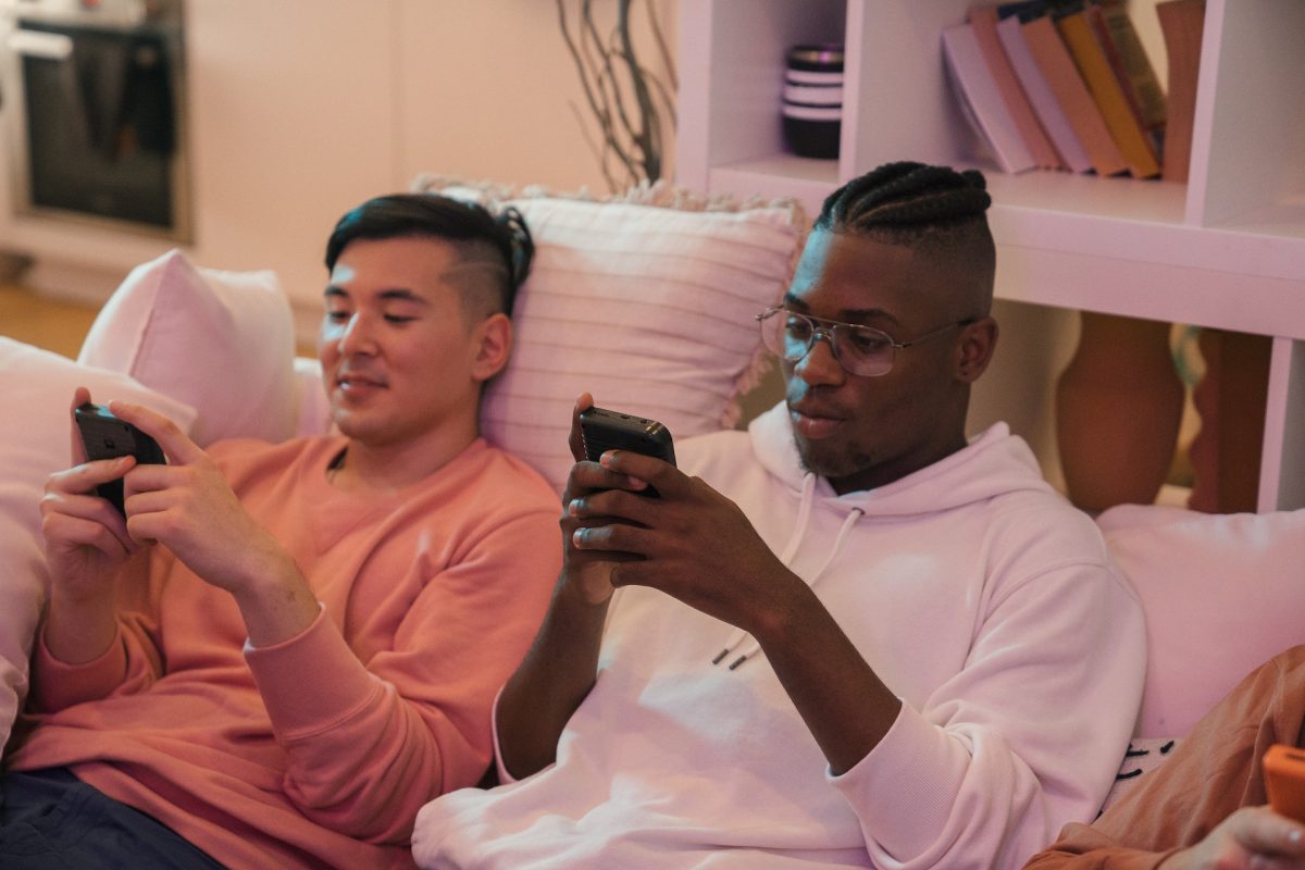 Two people scrolling on their phones while sitting on the couch.