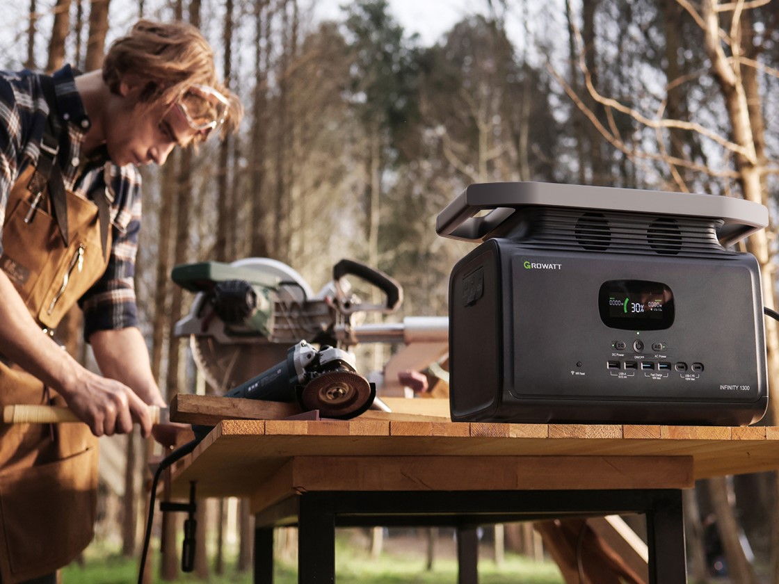 Man using INFINITY 1300 to power tools outdoors.