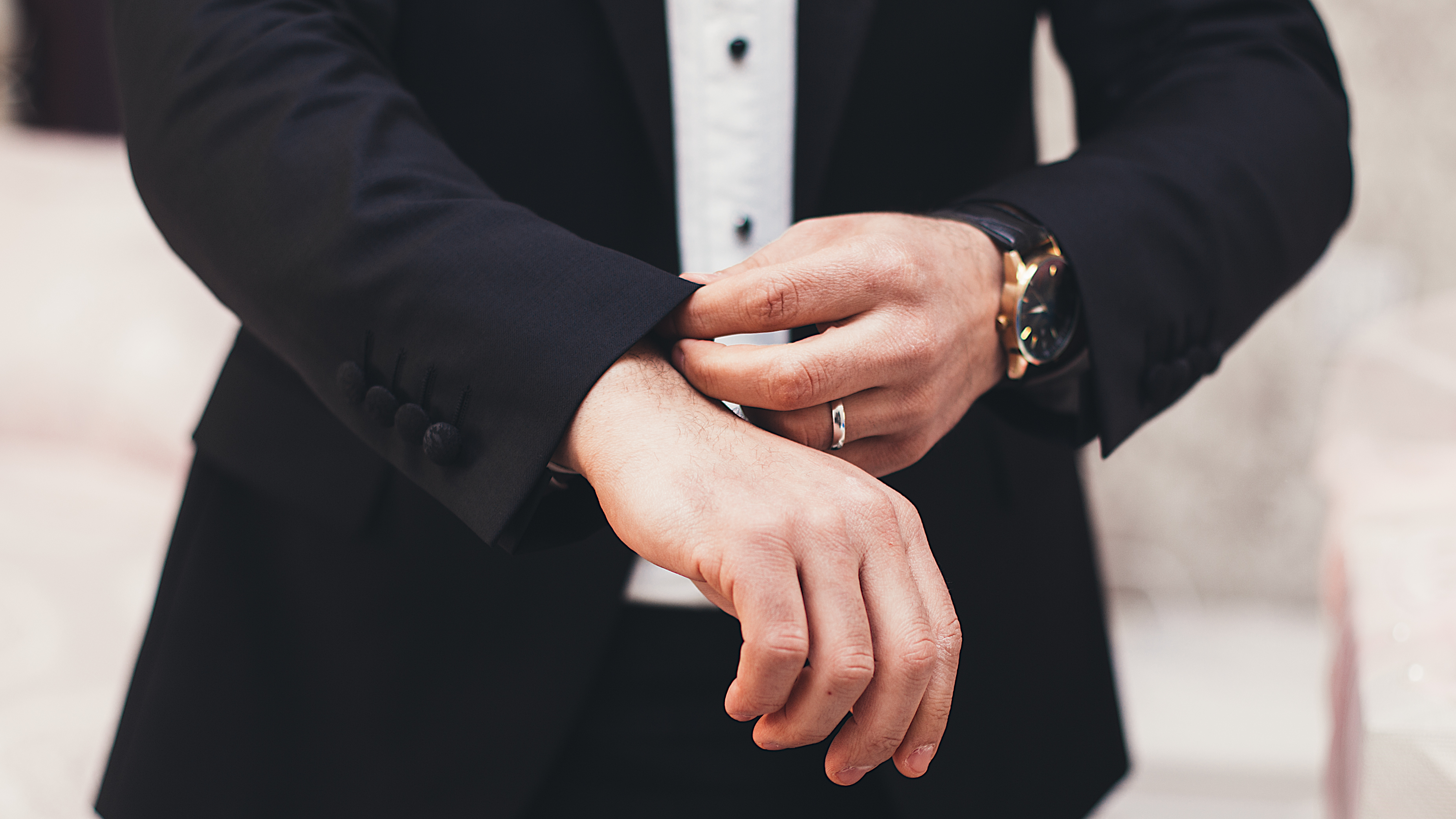 Man in black suit fixing his cuffs