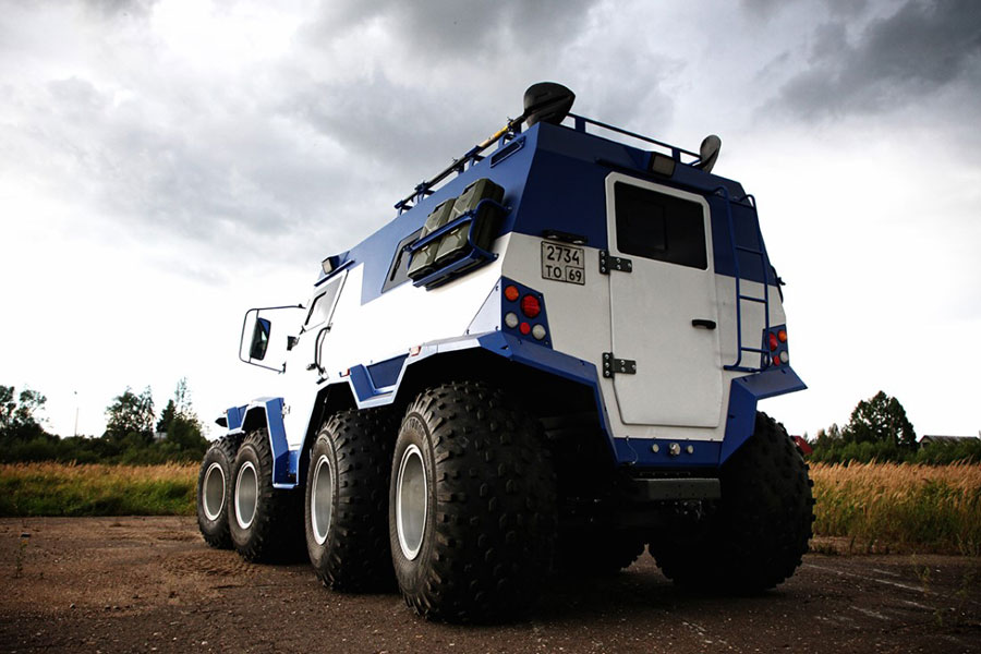 Avtoros Shaman 8x8 extreme overlanding vehicle parked in a field.