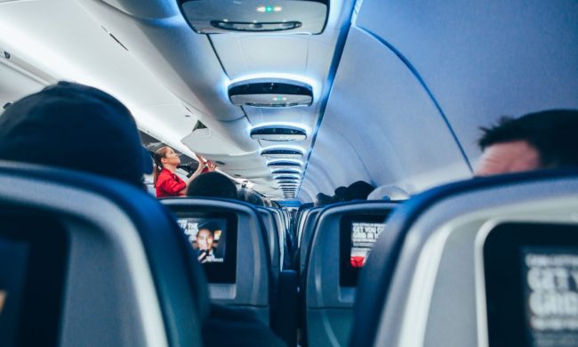 A flight attendant checking on the inside of a cabin on an airplane