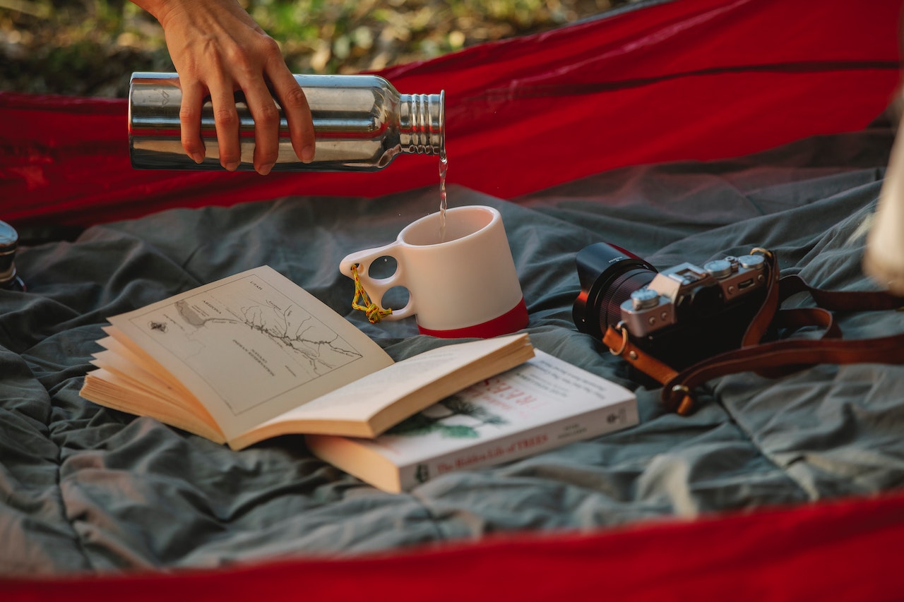 Pouring tea into a mug in a tent beside a book