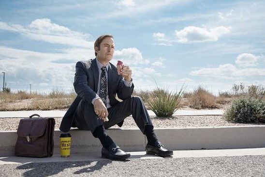 Bob Odenkirk sitting on the curb in loafers