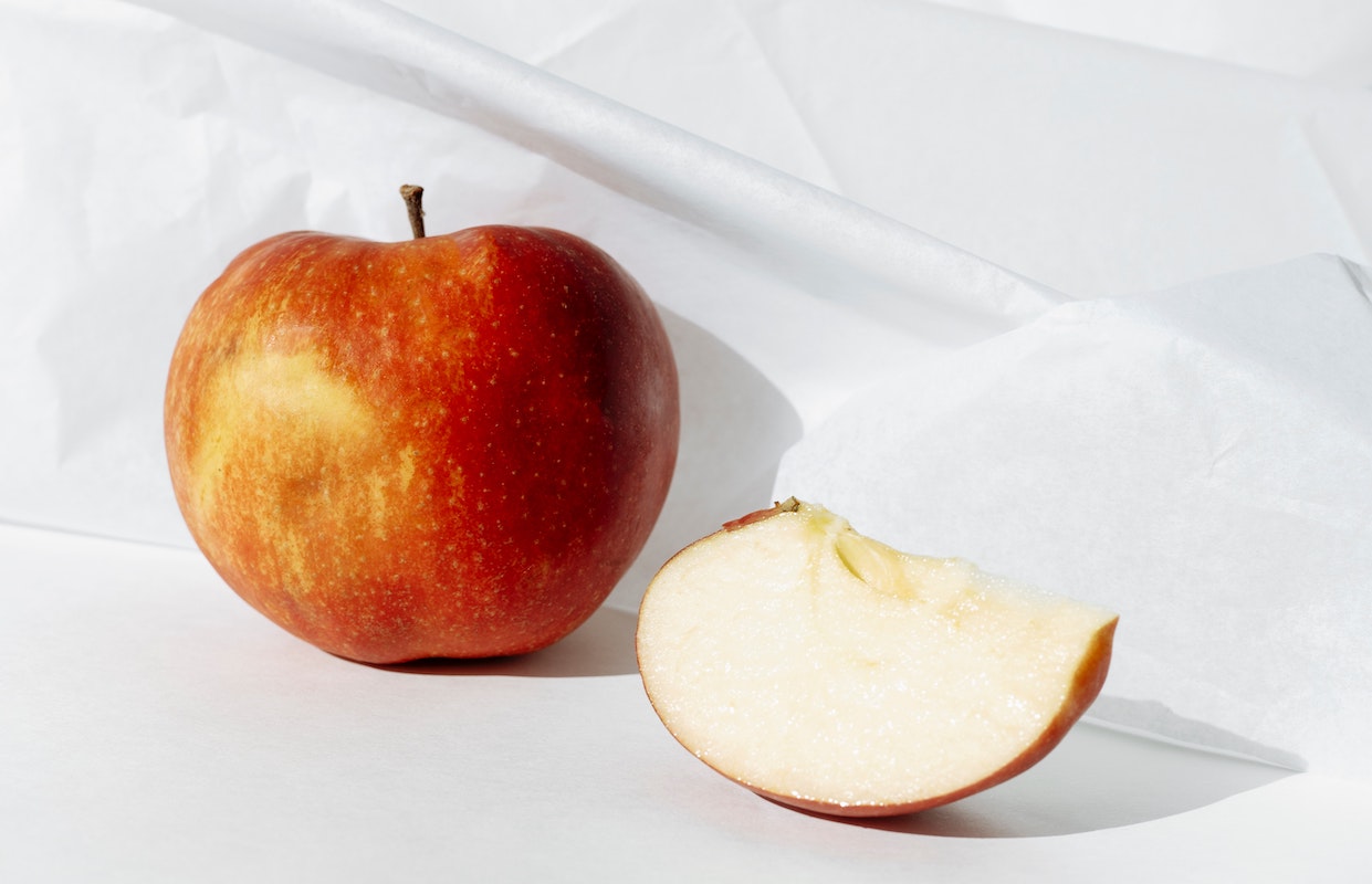 an apple slice and full apple on a white background