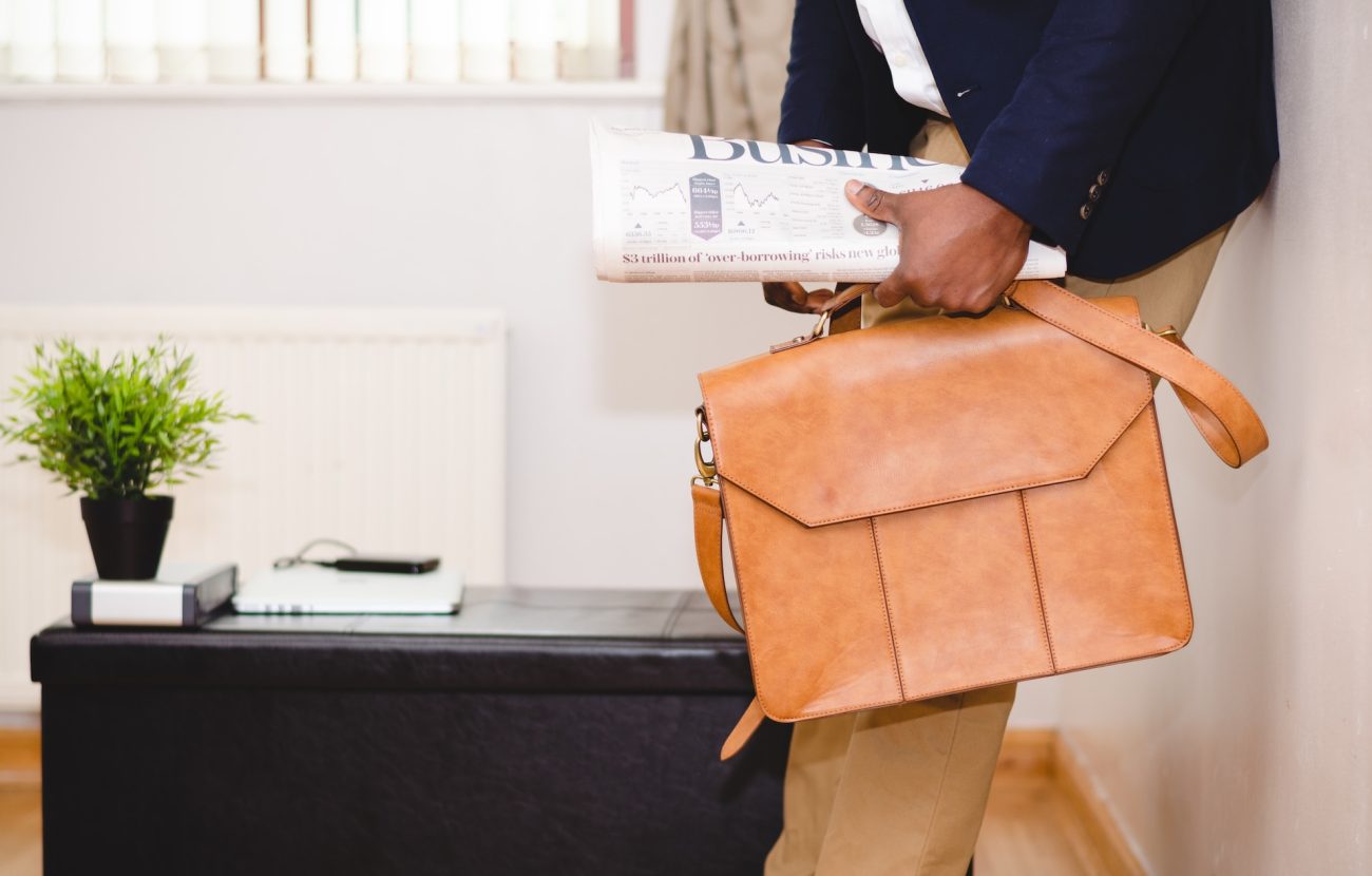 A man holding a briefcase and a newspaper.