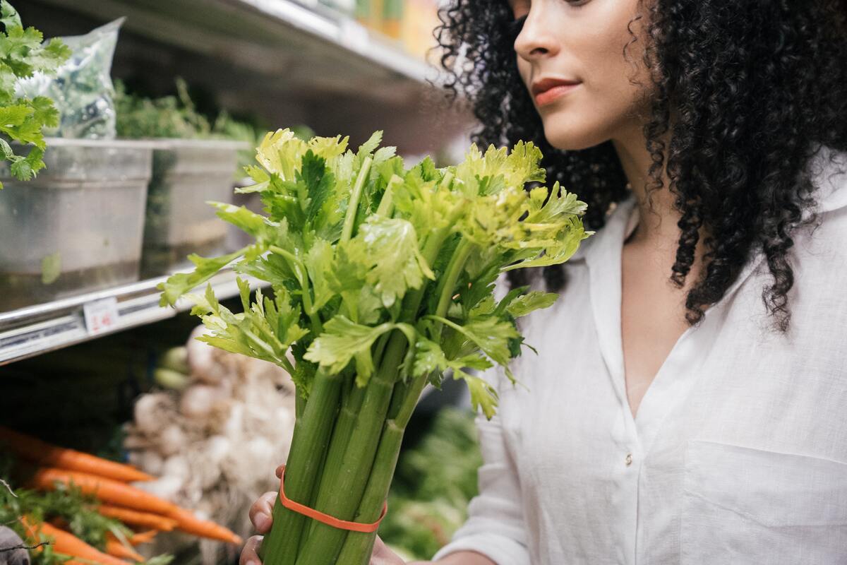 Woman holding celery in grocery store.