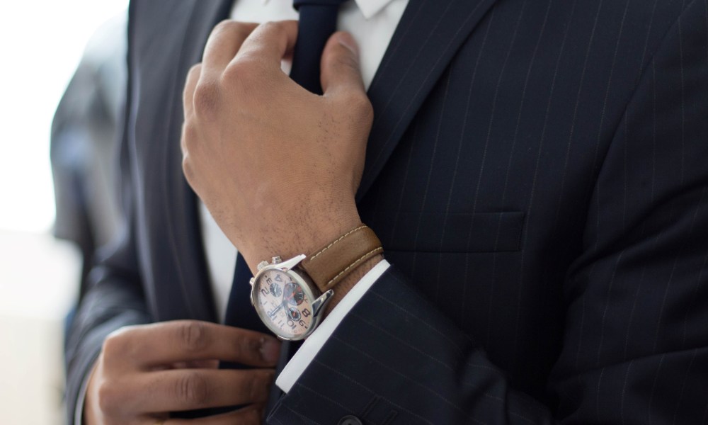 Man adjusting his tie wearing a watch