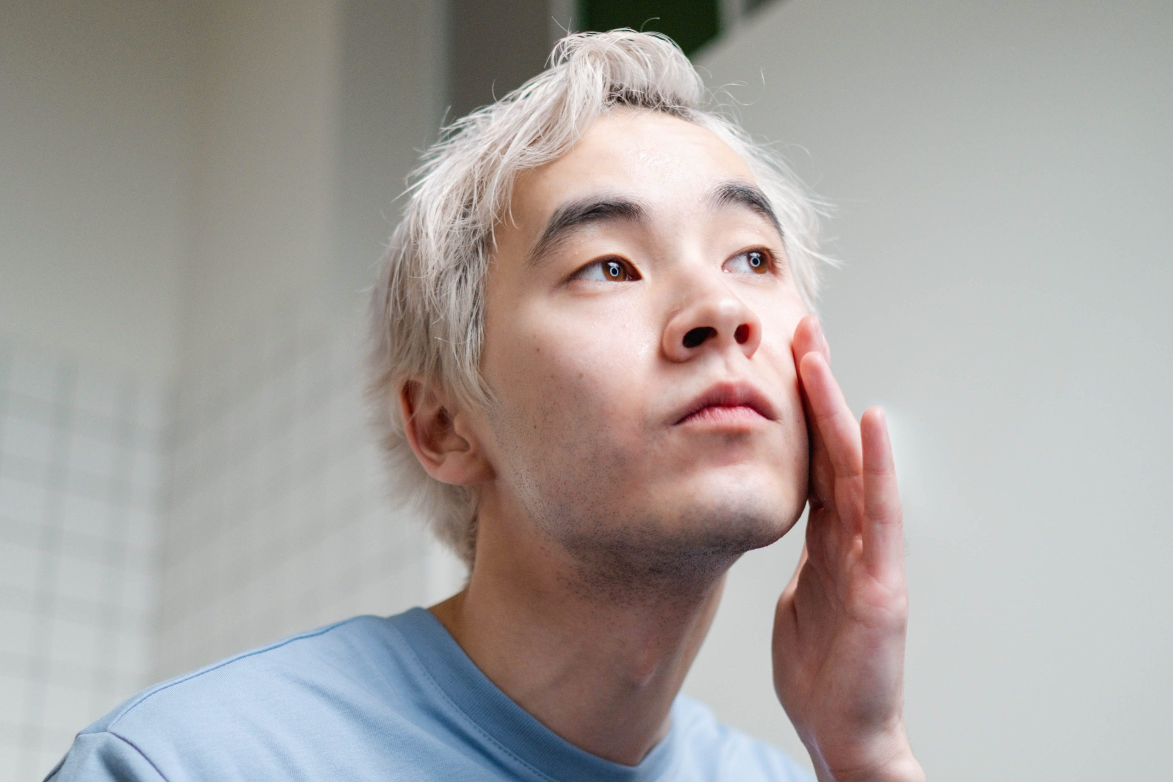 Man applying facial moisturizer in bathroom