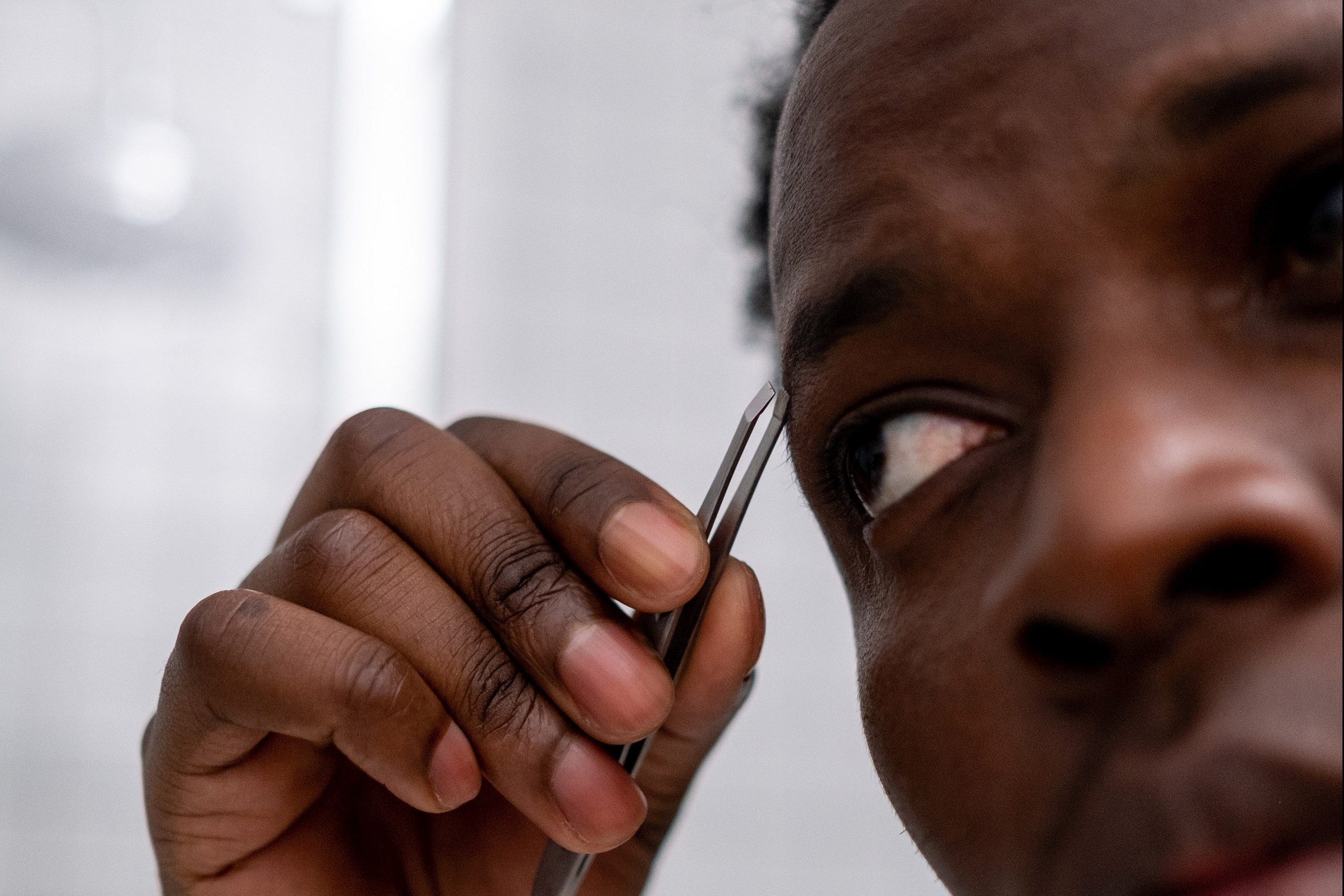 Man plucking eyebrows with tweezers