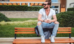 Man sitting on bench with ripped slim jeans