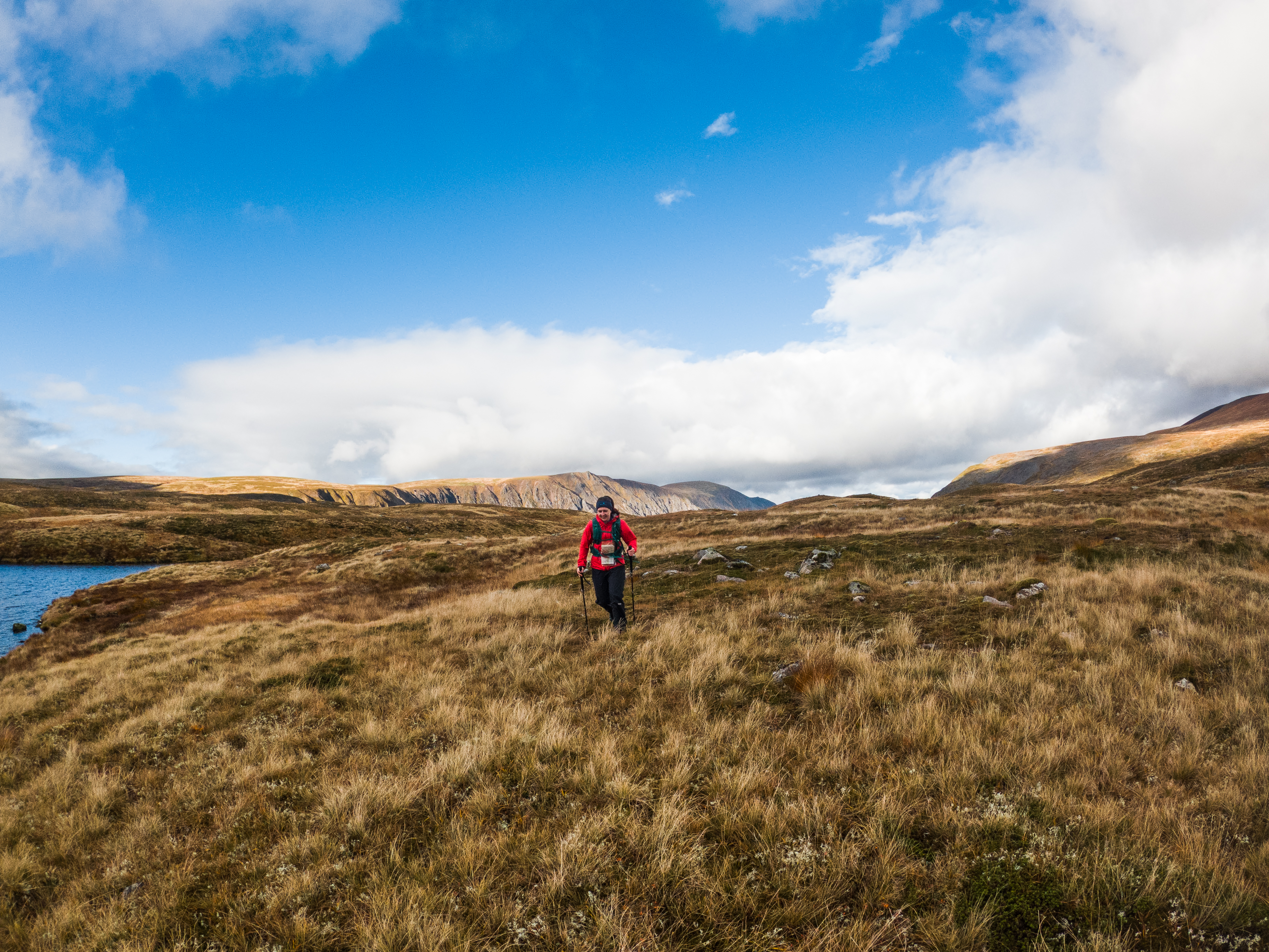 A person runs through the mountains with hiking poles.