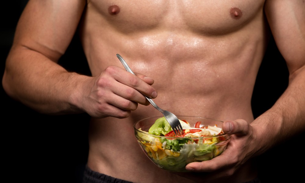 Shaped and healthy body building man holding a fresh salad bowl