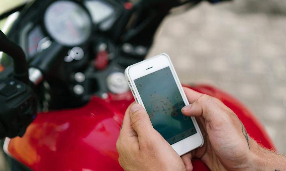 Close-up of phone in man's hands with motorcycle in background